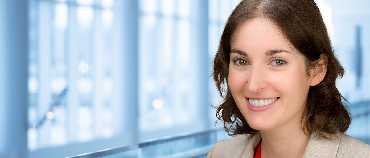 Woman with brown hair in lab coat holding a plastic device