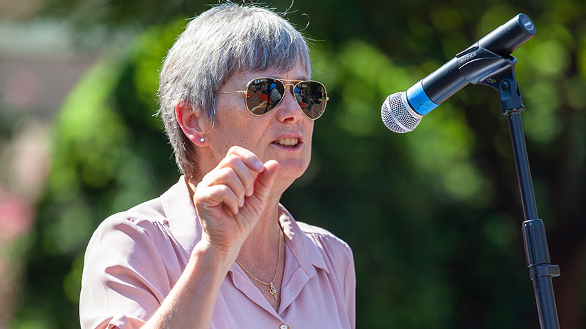 Woman with sunglasses speaking into a microphone