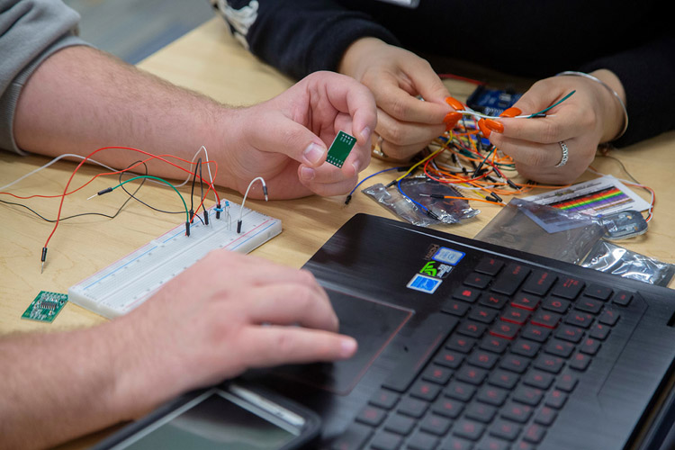 Two pairs of hands handling various electronics