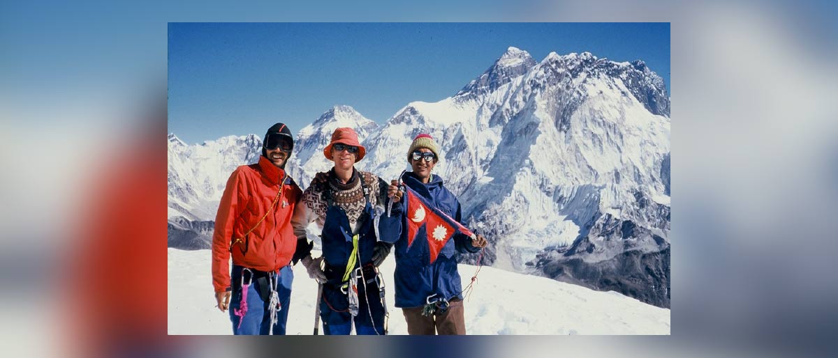 Three men in snow covered mountain area wearing climbing gear