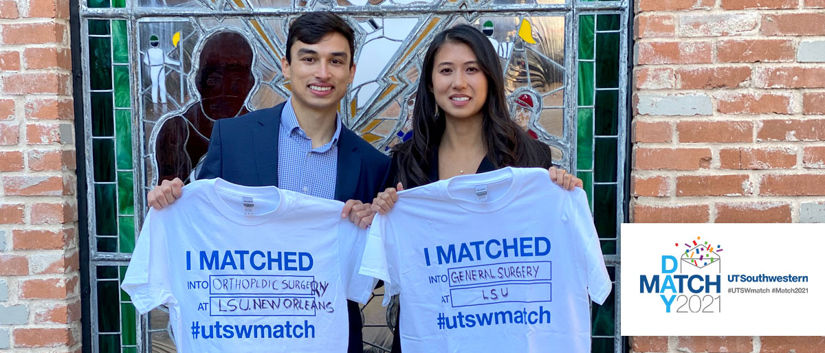 Two people holding Match Day tshirts and smiling