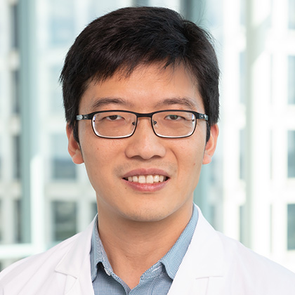 Dark-haired man wearing glasses and a lab coat.