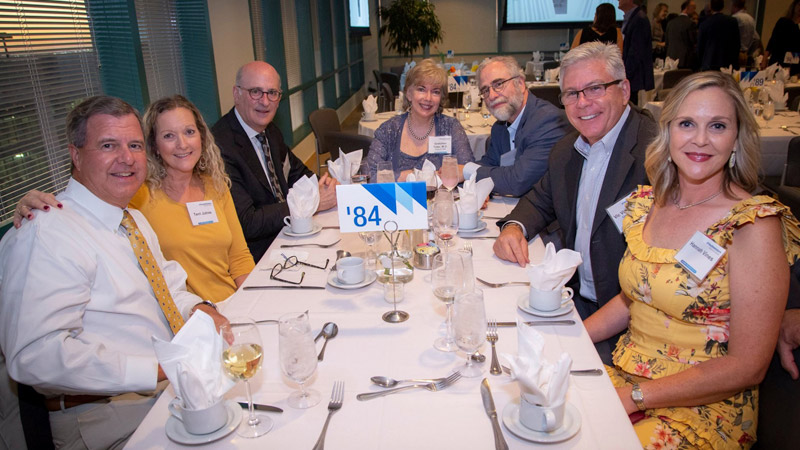 Seven people seated around a table wearing name badges