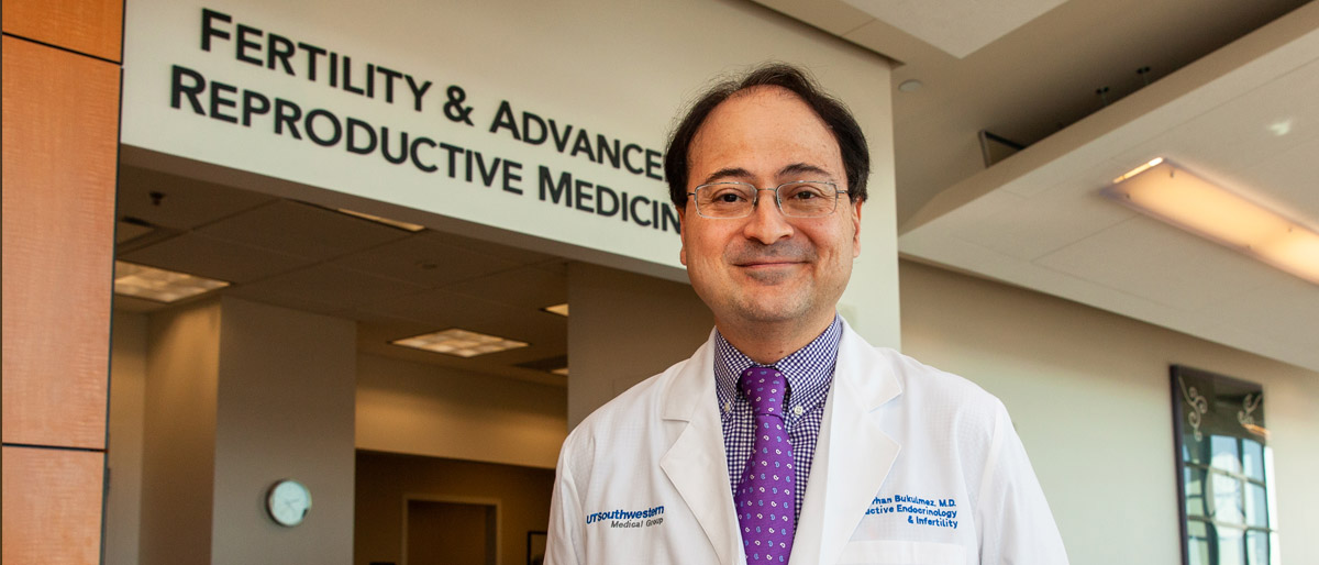 Man in lab coat standing in front of sign that reads fertility & advanced reproductive medicine