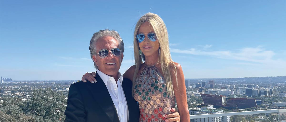 nicely dressed man and woman stand on balcony overlooking the city