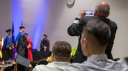 An audience member snaps a pic of graduates crossing the stage.
