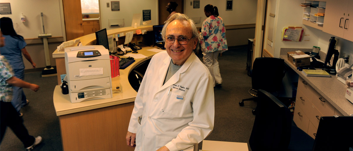 Man in lab coat in hospital with people in scrubs working