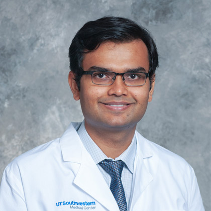 Man with glasses, dark hair, and wearing a lab coat