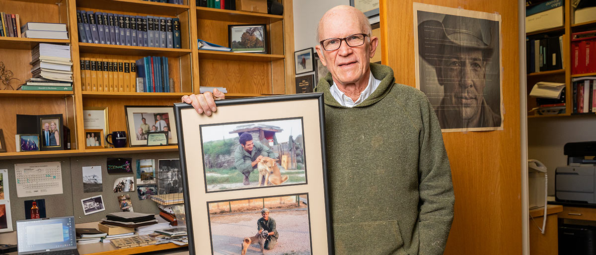 Man in office room holding photos