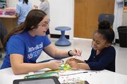 Teacher Natalie Cruz- Garcia praises her student as the girl succeeds in creating a colorful hand with yarn veins.