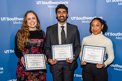 Three smiling people holding award certificates.