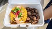 An employee shows off their fresh order of El Morro Churrasco from Mi Perú Borinqueño food truck.