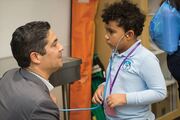Marcus Mobley listens to the heart rate of Roberto Gonzalez, M.D., Principal of Biomedical Preparatory.