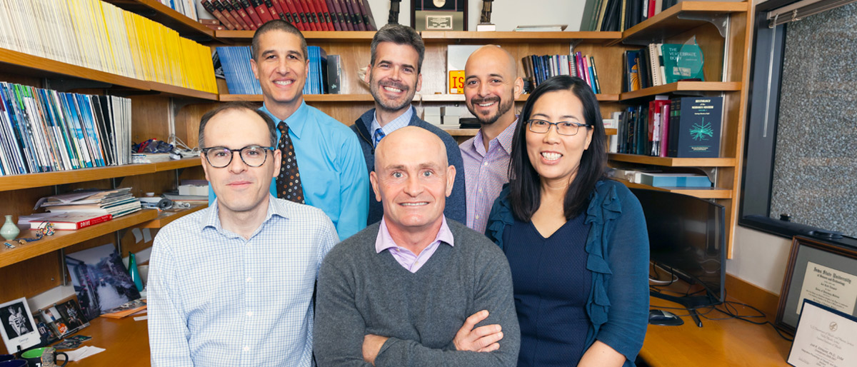 Group of six people in an office surrounded by bookshelves