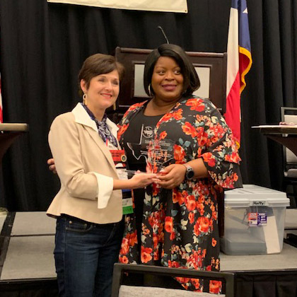 one woman handing another a glass award