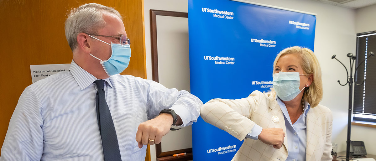 Man and woman in masks bumping elbows