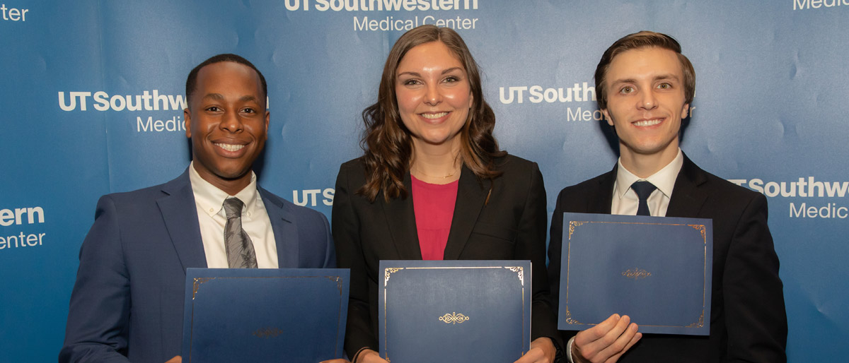 Three people holding certificates