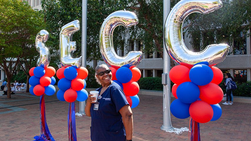 Woman in scrubs standing in front of SECC balloons