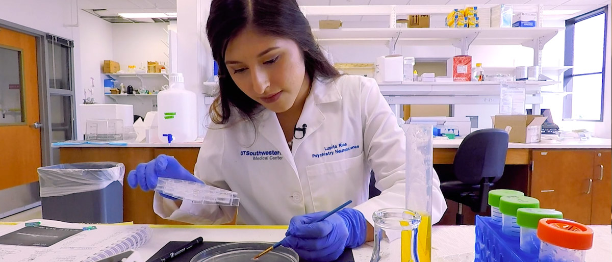 Young woman in a lab coat using a pipette