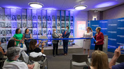 Organizers of the Celebrating Breakthroughs Together initiative and other UTSW executive leaders prepare to cut the ribbon to unveil the display on July 19.