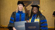 Madeline Milligan McGinnis, Ph.D., (left) and Bethany Smith, Ph.D., pose for a photo with their diplomas.