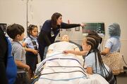 Students gather around an adult mannequin to learn about vital signs.