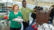 Administrative Coordinator Miroslava Ortiz (left) picks up a cup from Katherine Chitman of Nutrition Services at the fruit punch station. Red drinks at Juneteenth originate from fruits of two West African plants: the kola nut and hibiscus.