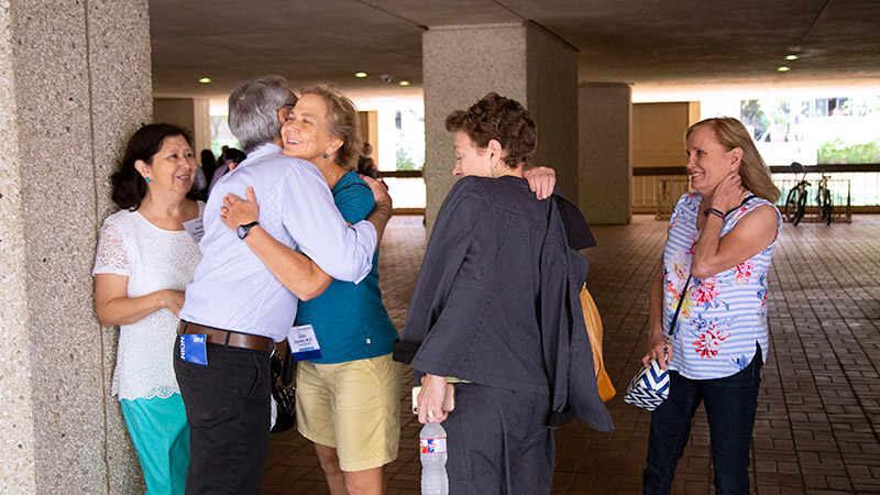 Group of people meeting, two of them hugging