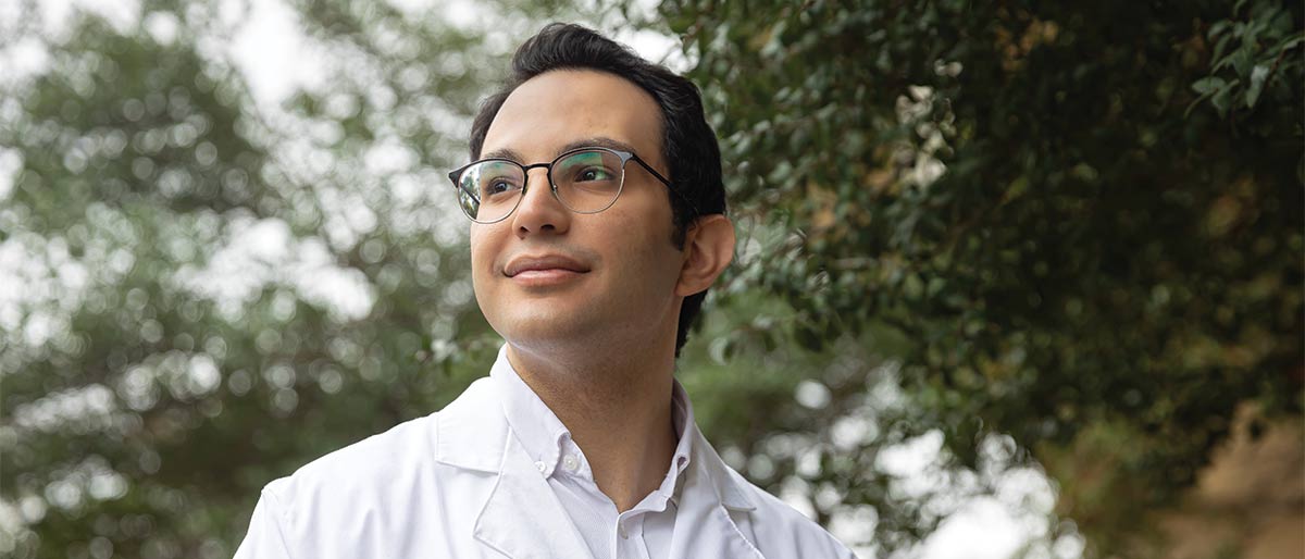 man in white lab coat surrounded by trees