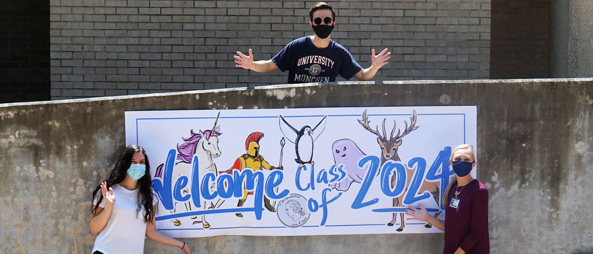 Three students masked, distanced, holding a welcome class of 2024 sign