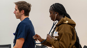 Medical student Kurt Ottman, left, assists students with listening to breath sounds during a mock physical exam.