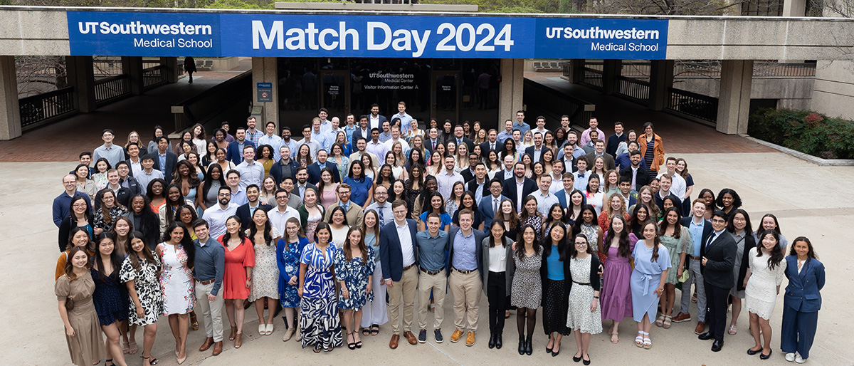 All the matched students gathered outside in front of a banner. Banner copy: UT Southwestern Medical School - Match Day 2024 - UT Southwestern Medical School