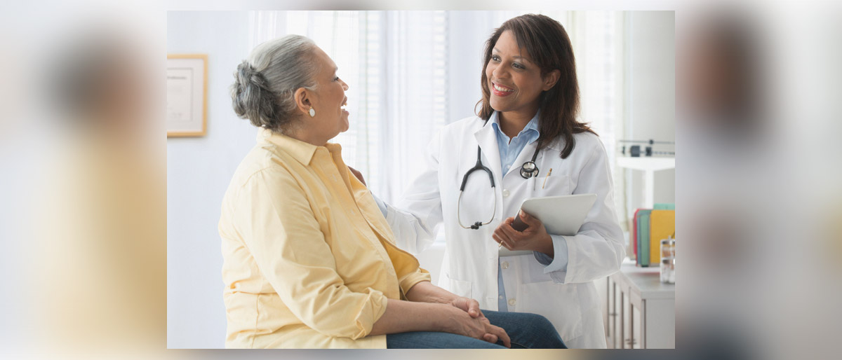 Doctor speaking with older patient, both smiling