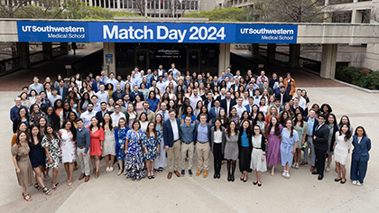 All the matched students gathered outside in front of a banner. Banner copy: UT Southwestern Medical School - Match Day 2024 - UT Southwestern Medical School