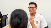A senior medical student conducts a horizontal gaze test on a high school student during a physical exam session led by medical students and faculty.