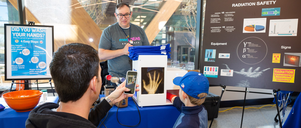 Boy putting arm into x-ray simulation box at table