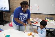 Shemyia Taylor, one of the STEM teachers, helps a student with his craft project, explaining how to make yarn look like veins in a hand.