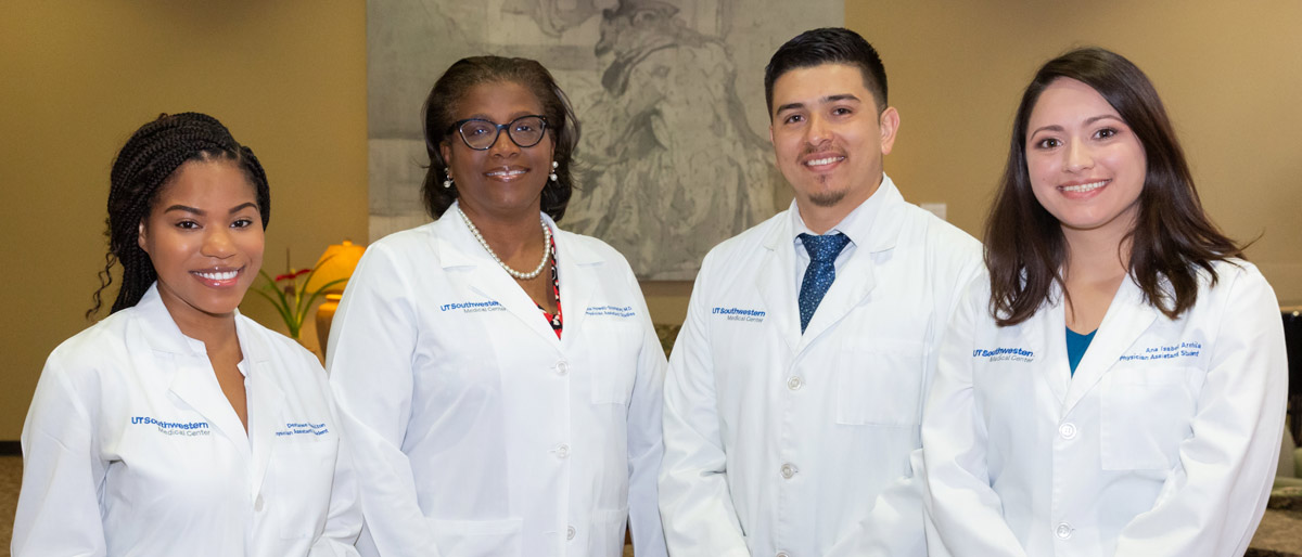 Group of four people in white lab coats smiling