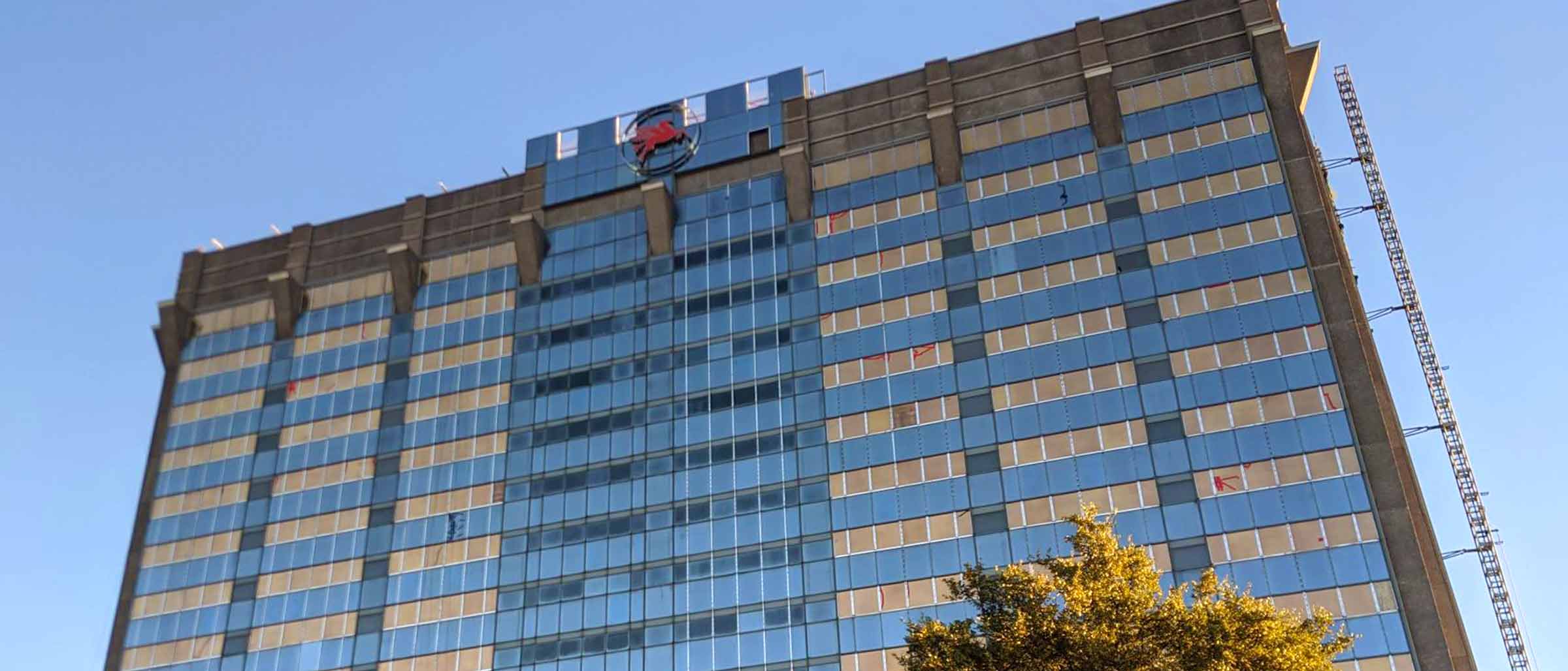 Rendering of tall glass building with red pegasus on top