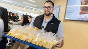 Nutrition Services team member Stephen Cepeda carries a tray full of fresh baked jalapeno cornbread.