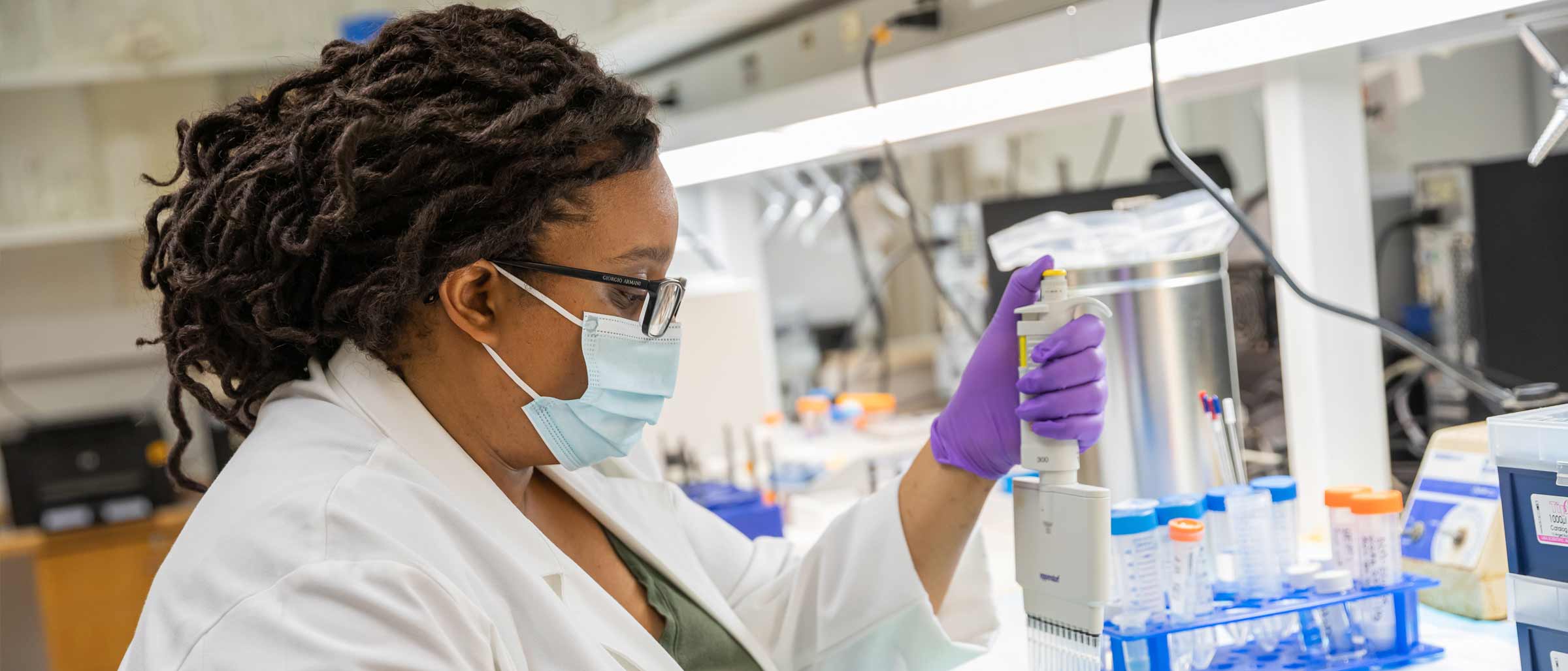 Woman with mask and lab coat on working in a lab