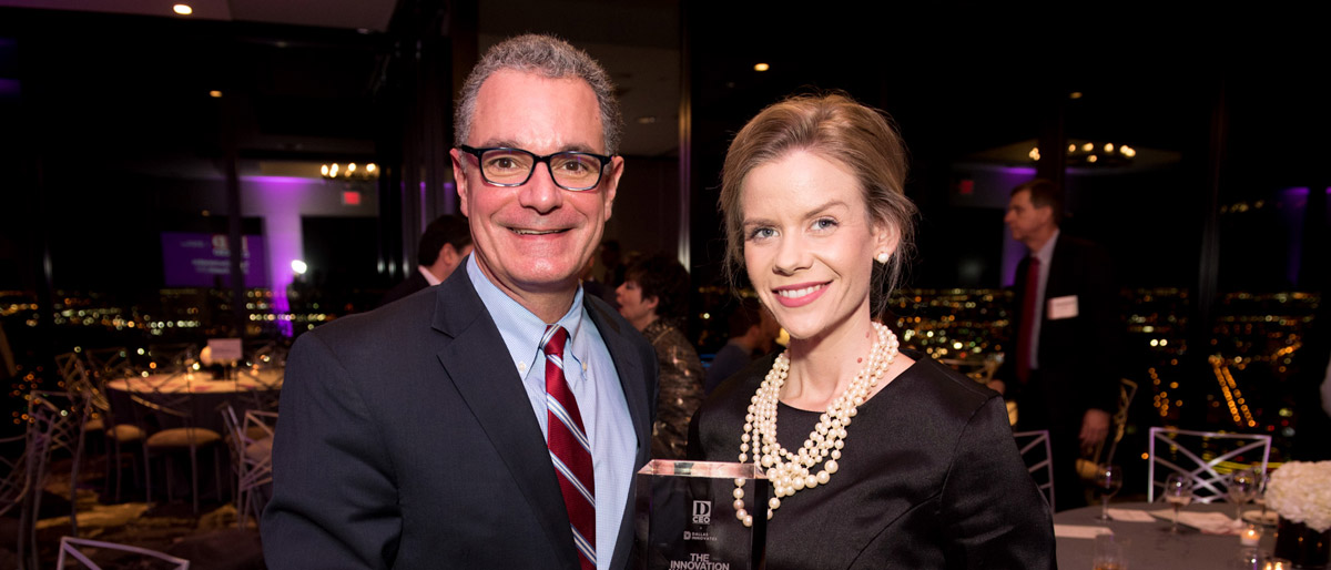 Man and woman smiling, holding a glass award