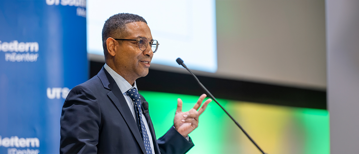 Well-dressed man speaks into a microphone.