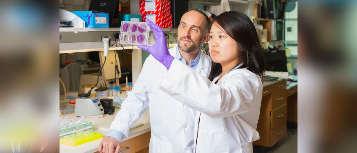 Woman and man in lab coats looking at material