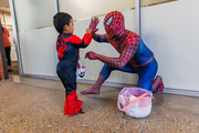 This young Spiderman gives a high-five to a fellow Spiderman.