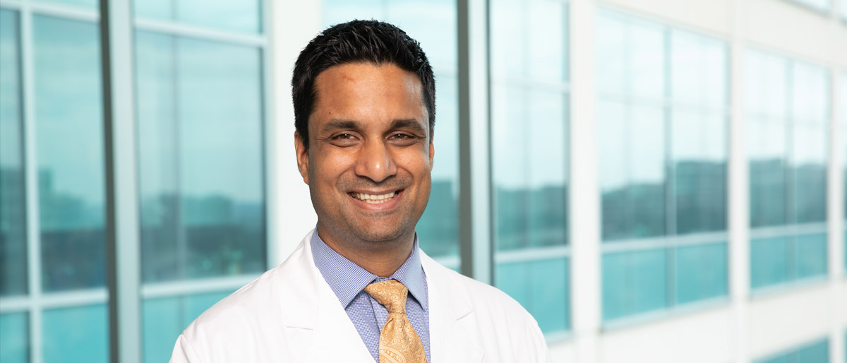 Man with short dark hair wearing a white lab coat