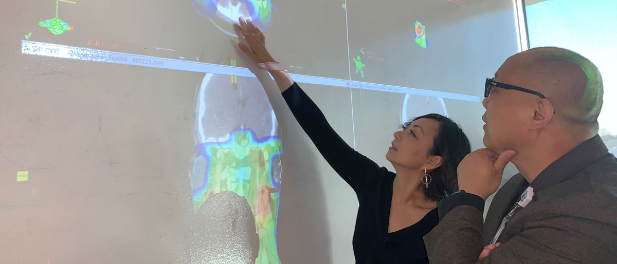 Woman pointing to projection of brain scan while talking to man