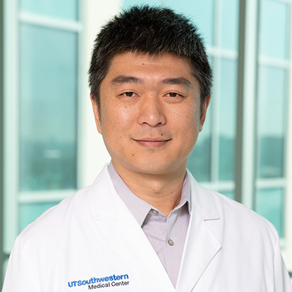 Man with short dark hair wearing a white lab coat.