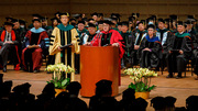 Conferring degrees to the graduates were UTSW President Daniel K. Podolsky, M.D., at the podium, and EVP for Academic Affairs, Provost, and Medical School Dean W. P. Andrew Lee, M.D., to his left, surrounded by more UTSW faculty.