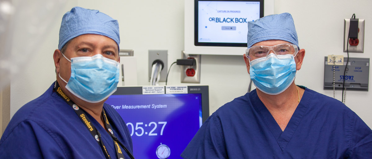 Two men in scrubs, surgical masks